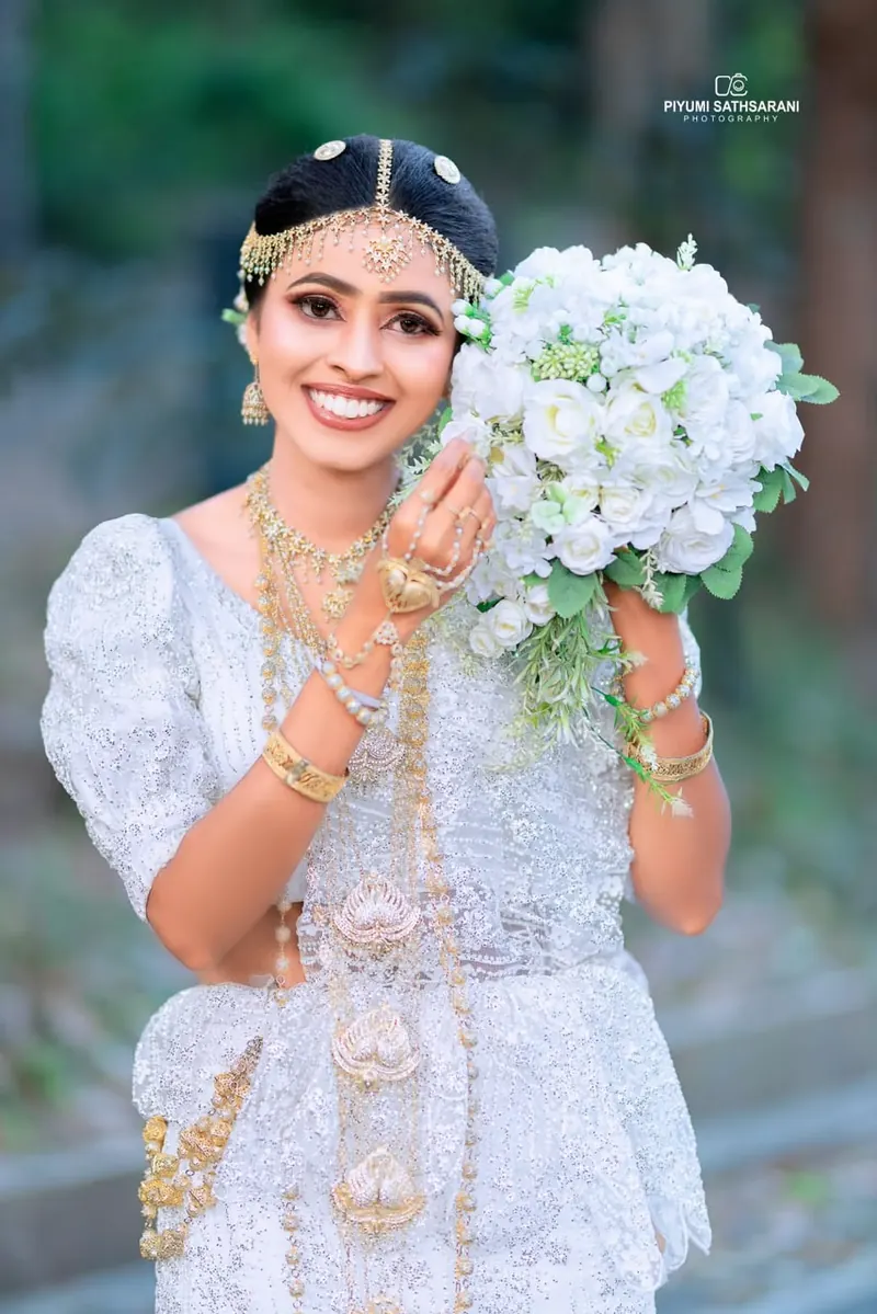 Smiling bride holding a white rose bouquet against her cheek