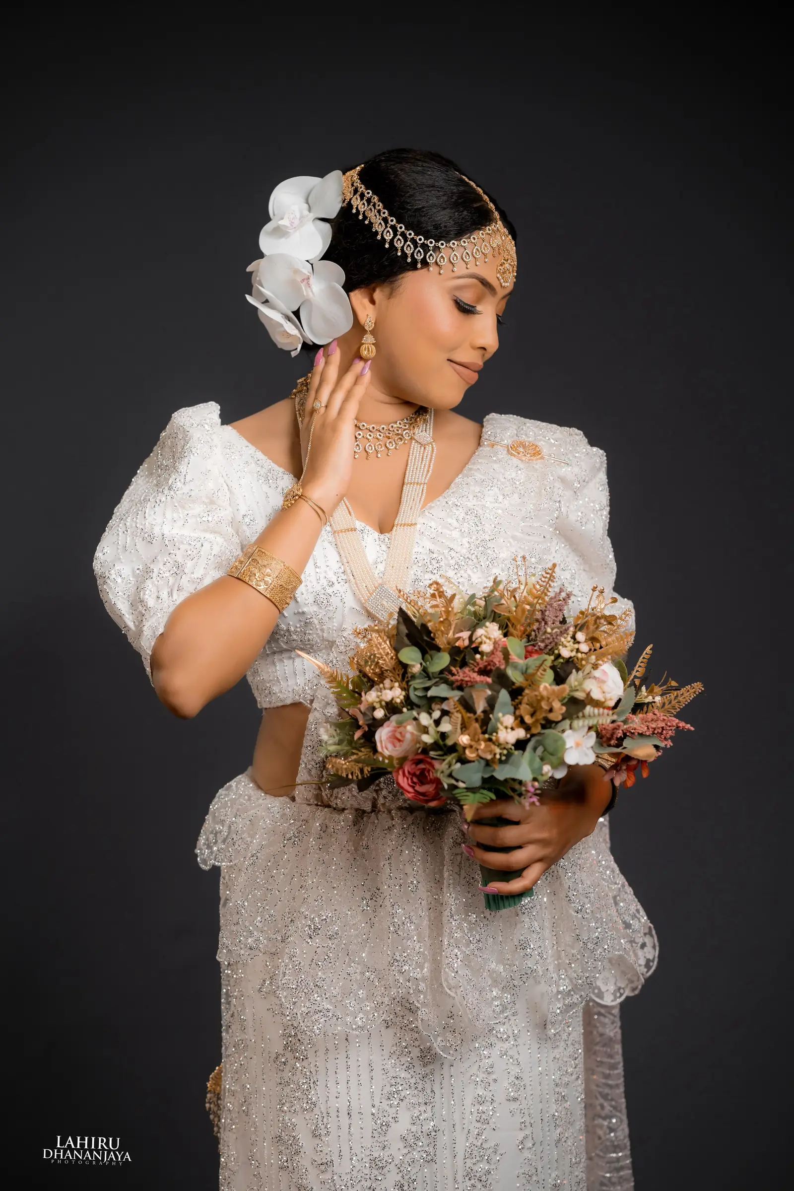 Bride with an orchid in her hair holding a bouquet of dried flowers