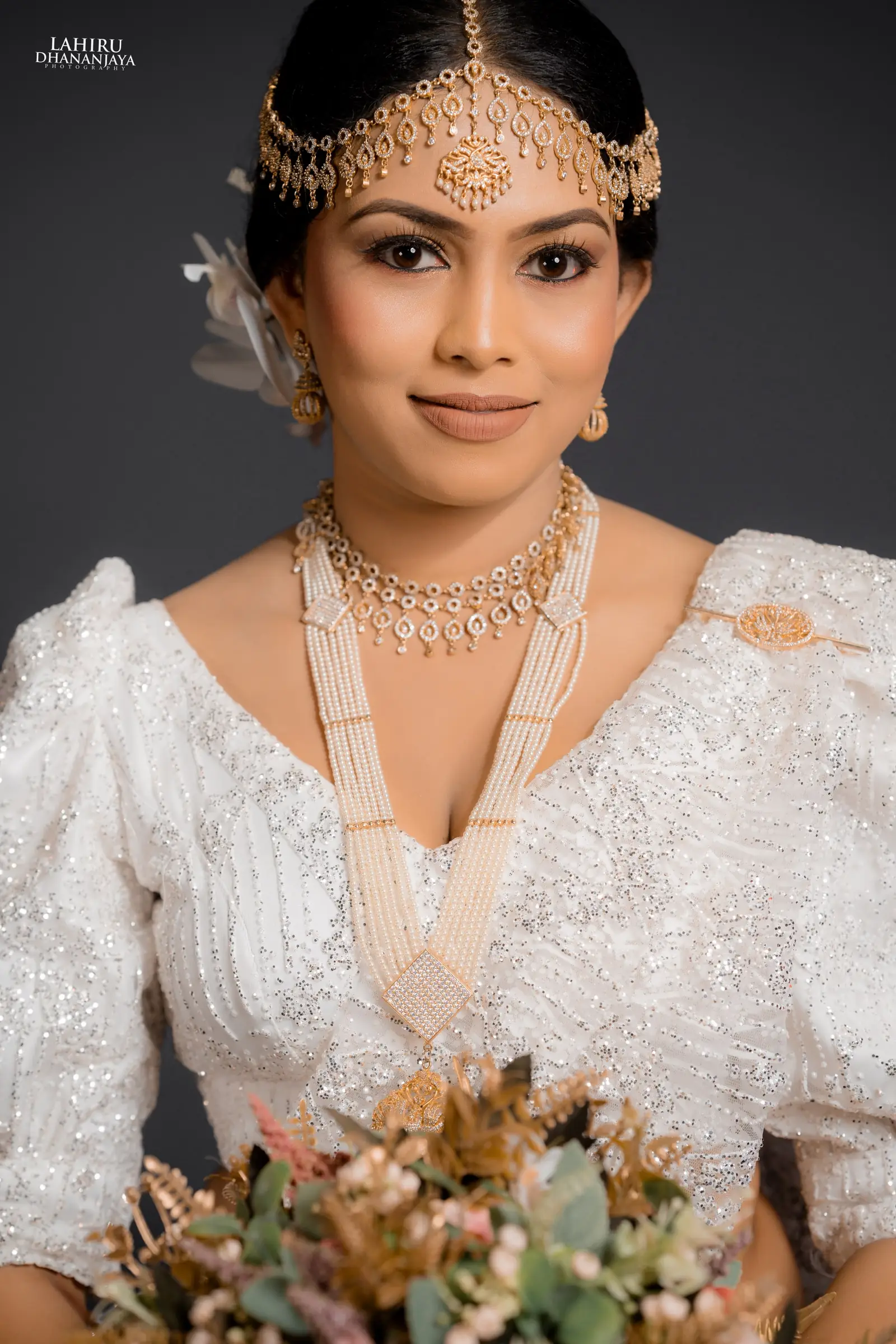 Bride in a white lace osariya with layered pearl strands and gold jewellery
