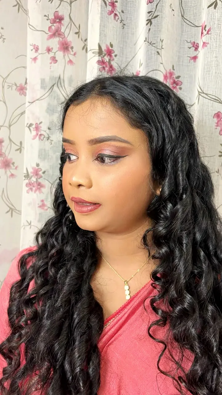 Client with long curls and soft party makeup in a pink saree
