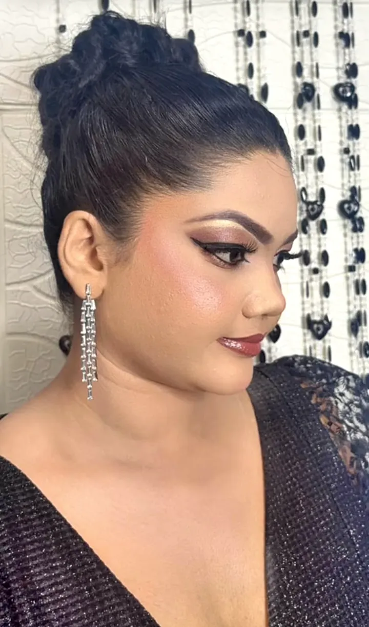 Client with a high bun, winged eyeliner and evening makeup