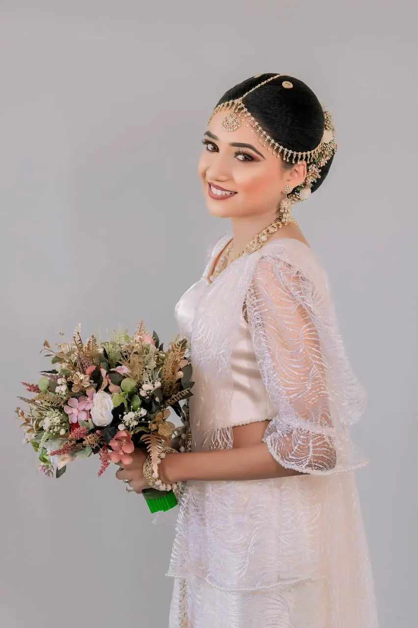 Bride in a white lace blouse with a bouquet against a soft lilac backdrop